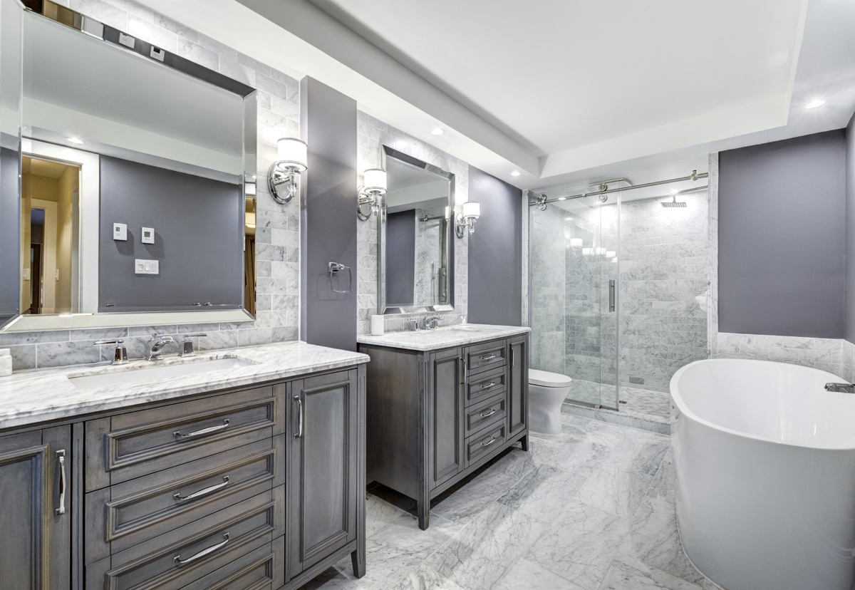 A newly renovated bathroom with two separate vanities, a free-standing bathtub, separate shower, a grey and white marble floor, CK Contracting, Custom Bathroom Remodel, Mt. Pleasant, S.C.